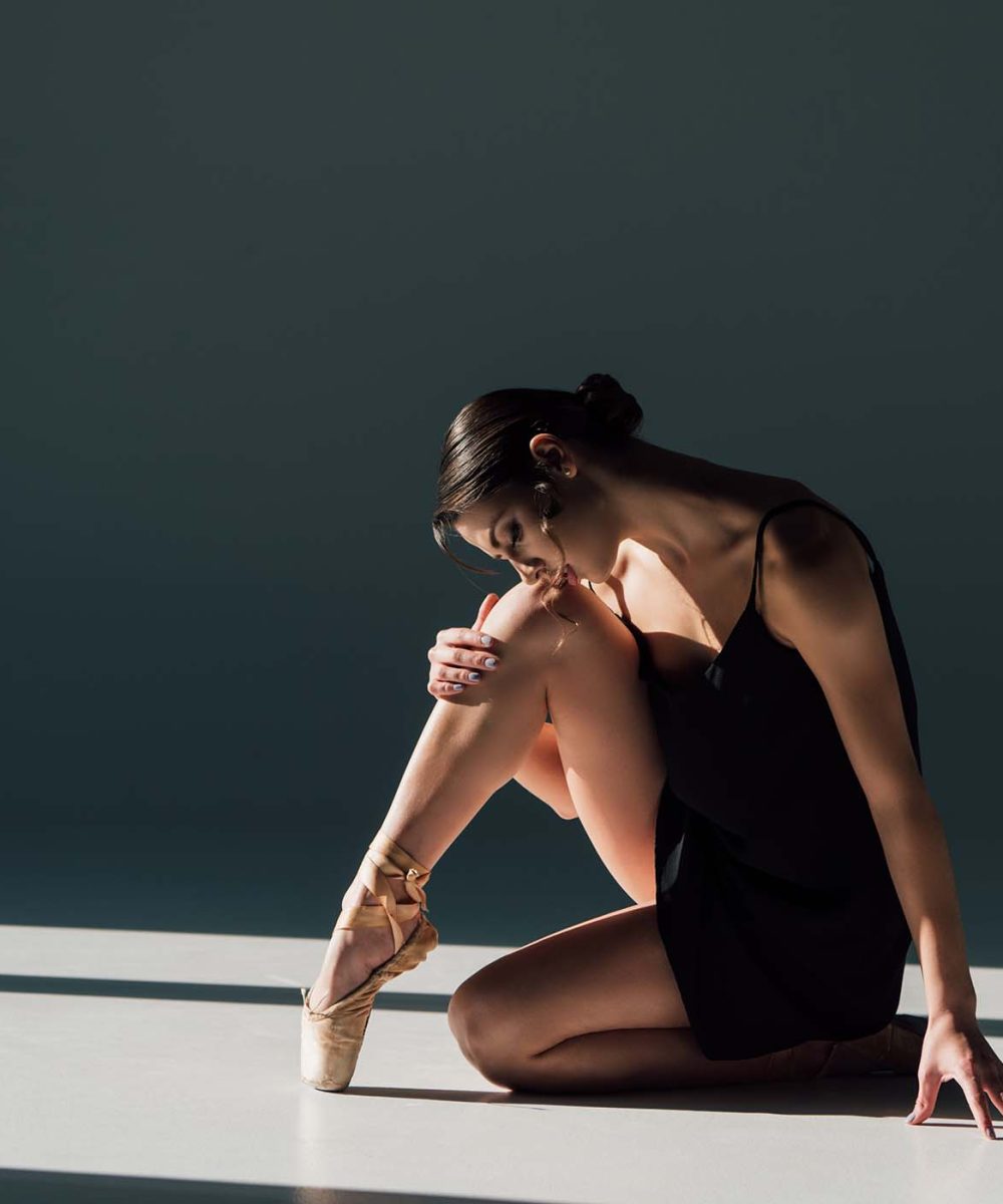 beautiful-ballerina-in-black-dress-sitting-in-sunl-ATBAEKJ.jpg