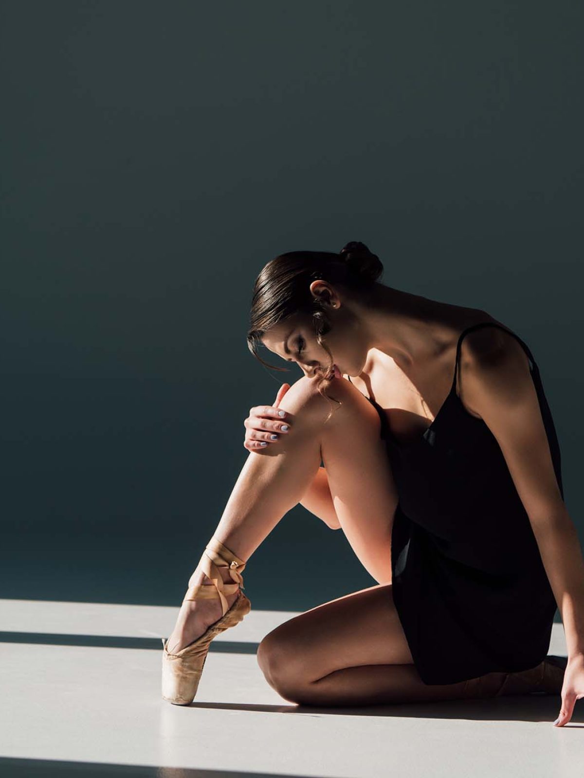 beautiful-ballerina-in-black-dress-sitting-in-sunl-ATBAEKJ.jpg